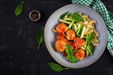 Italian pasta. Fusilli with meatballs, cucumber and basil on dark background. Dinner. Slow food concept. Top view, flat lay