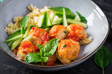 Italian pasta. Fusilli with meatballs, cucumber and basil on dark background. Dinner. Slow food concept.
