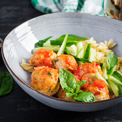 Italian pasta. Fusilli with meatballs, cucumber and basil on dark background. Dinner. Slow food concept.
