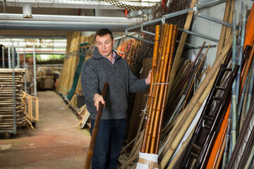 Young man choosing bamboo stakes at garden material store