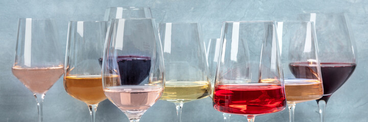 Variety of wine colors panorama. Red, rose, and white wine in elegant glasses at a tasting at a...