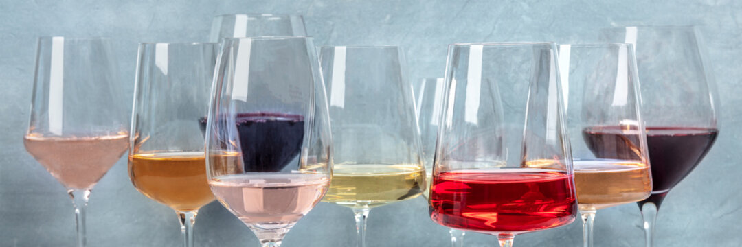 Variety of wine colors panorama. Red, rose, and white wine in elegant glasses at a tasting at a winery. Winetasting event