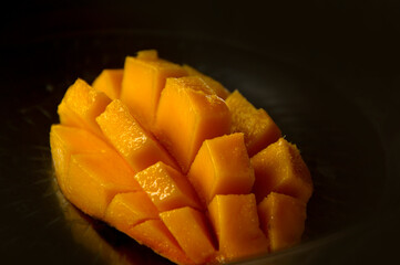 Mango slice cut to cubes close-up isolated on black background