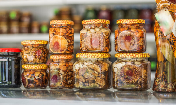 A Row Of Cans With Canned Fruits And Nuts In Honey On The Shelves