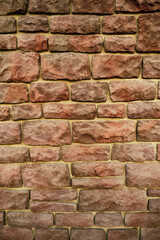 Textured background of the wall made of natural old red stone, close-up.