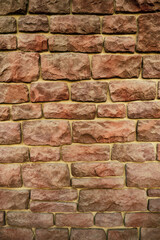 Obraz premium Textured background of the wall made of natural old red stone, close-up.