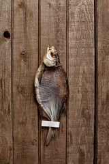 Sun-dried bream with paper label on tail on wooden background