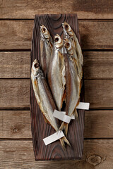 Salted air-dried sabrefish with labels on tails on wooden serving plate