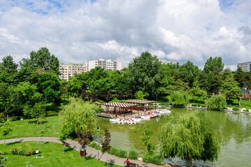 Landscape with lake and vivid green trees in Drumul Taberei Park (Parcul Drumul Taberei) also known as Moghioros Park, in Bucharest, Romania, in a cloudy summer day.
