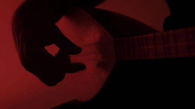 Close up shot of Playing Kopuz which is a string instrument named Baglama with three strings on a red background.