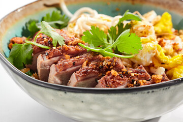 Pan asian traditional dish - fried rice with vegetables, shredded omelette and duck. Oriental wok with rice on white background. Nasi goreng with duck on isolated background with shadows.