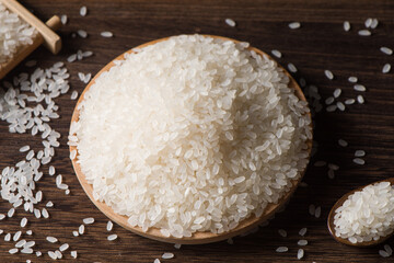 Dry white rice in wood spoon on rice background