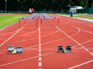 Running track with blurry running person, athletic obstacles