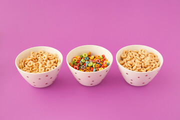 Bowls with cornflakes on color background. Concept of uniqueness