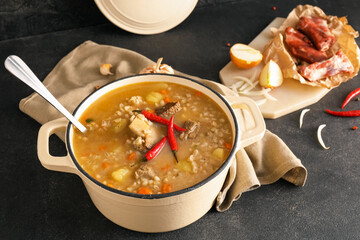 Cooking pot with tasty beef barley soup on table