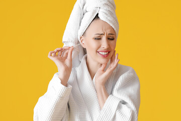 Young woman cleaning ears with cotton bud on color background