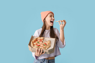 Beautiful young woman eating tasty pizza on color background