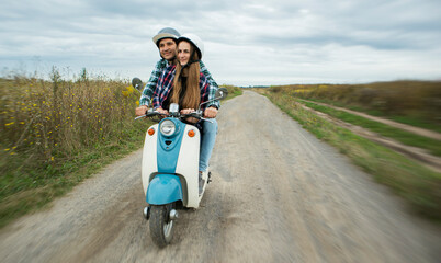 A couple of lovers riding the retro scooter through the countryside