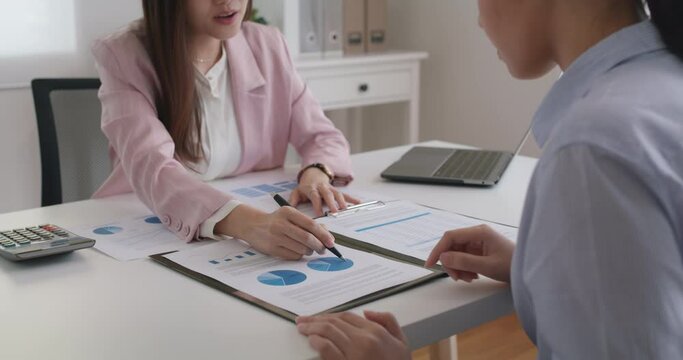 Asia stock trader agent or Sale tax loan broker advice brief and point hand to graph report talk to client at office desk show budget chart data or legal result on claim form. Trust will in work plan.