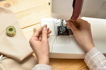 Woman using sewing machine on wooden background