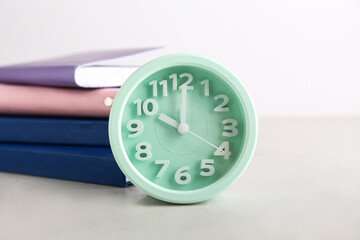 Stylish alarm clock with books on white background