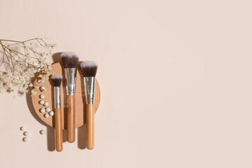 Set of makeup brushes with powder and flowers on color background