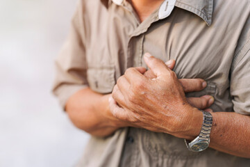 Close-up of an elderly man's hand held his chest in pain. Concept of heart disease. - obrazy, fototapety, plakaty