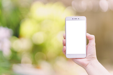 Woman's hand holding a smartphone with white blank screen for texting - on blurled background.