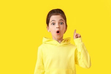 Cute little girl with raised index finger on color background