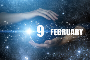 February 9th. Day 9 of month, Calendar date. Human holding in hands earth globe planet with...