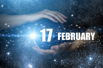 February 17th. Day 17 of month, Calendar date. Human holding in hands earth globe planet with...