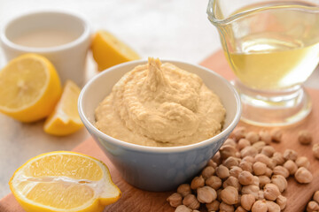 Bowl with tasty hummus, chickpea and lemon on light background