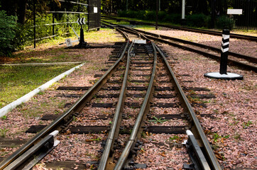 Fototapeta na wymiar Narrow gauge railway tracks with switches and interchanges at Kyiv Children's Railway in Syretsky Park. Geometrical structures, thresholds, gravel and screws