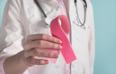 Doctor holding pink breast cancer awareness ribbon. Medicine and healthcare concept, women's...