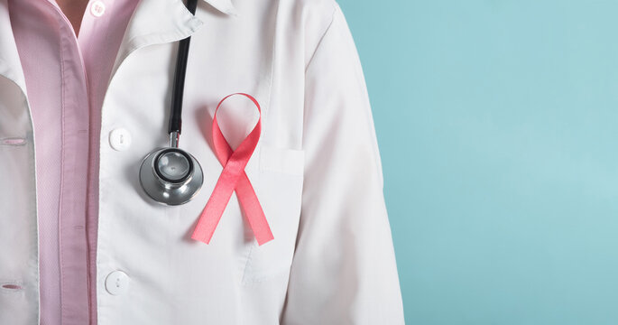 Breast cancer awareness concept. Doctor with pink ribbon and medical stethoscope on light blue background. Close up, banner