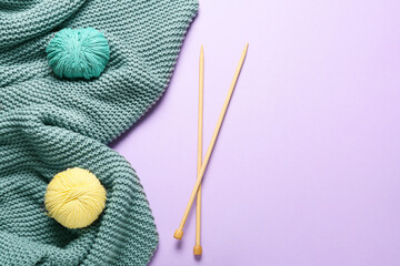 Yarn with knitting needles and plaid on color background