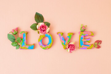 Fototapeta na wymiar Neon sign of love with fresh roses on letters. Autmn creative concept. Flat lay on pastel pink background.