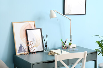 Modern workplace with stylish pictures near color wall