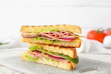 Board with tasty sandwiches on light background, closeup