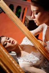 a beautiful young woman in a lace robe looks at her reflection in the mirror.