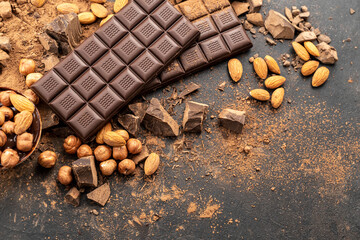 Almonds and hazelnuts with melted dark chocolate. Melted milk chocolate, cocoa powder, pieces and nuts on black background. Cooking handmade chocolate bars, desserts, sweets. Confectionery craft