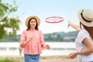 Fototapeta premium Beautiful young women playing frisbee outdoors