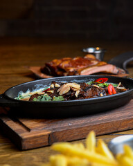 Meat with vegetables served with sauce in a pot over rustic wooden background. Rustic style dinner