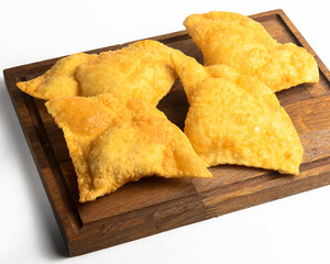 Homemade chebureks with meat and onion on wooden board over white background.