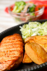 Grilled Chicken Steak with fried potatoes in rural style and coleslaw salad served in a tray over white background.