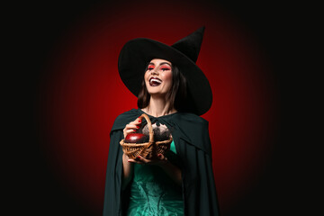 Young witch holding basket with apple on dark background