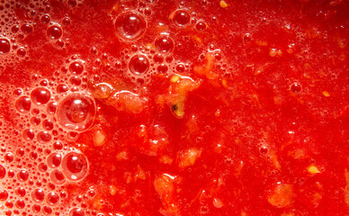Tomato juice with pulp close-up. On the surface bubbles of different sizes and foam. 