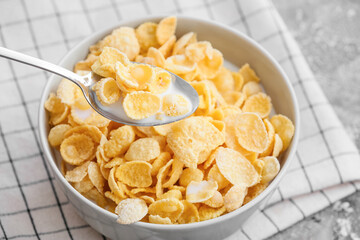 Eating of tasty corn flakes on grunge background, closeup