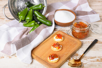 Delicious crackers with cottage cheese and jalapeno pepper jam on wooden table