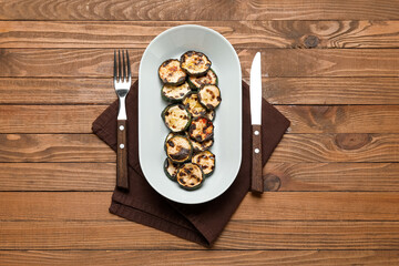 Plate with tasty grilled zucchini on wooden background